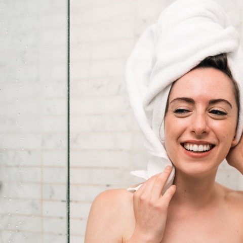 Κοπέλα με πετσέτα στα μαλλιά και το σώμα βγαίνει από το ντους