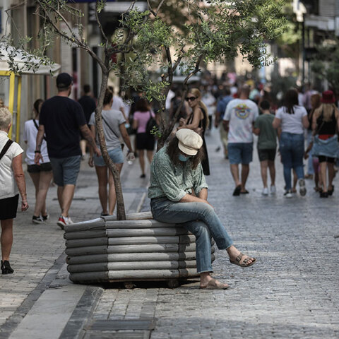 Άνδρας με μάσκα για τον κορωνοϊό κάθεται σε παρτέρι στο κέντρο της Αθήνας