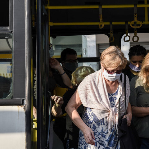 Επιβάτες με μάσκα για τον κορωνοϊό κατεβαίνουν από λεωφορείο στο κέντρο της Αθήνας