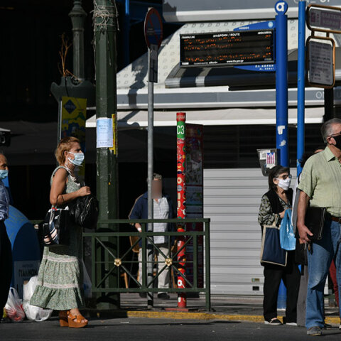 Πολίτες με μάσκα για τον κορωνοϊό περιμένουν το λεωφορείο στη στάση