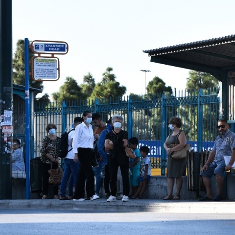 Άνθρωποι με μάσκα σε στάση λεωφορείου