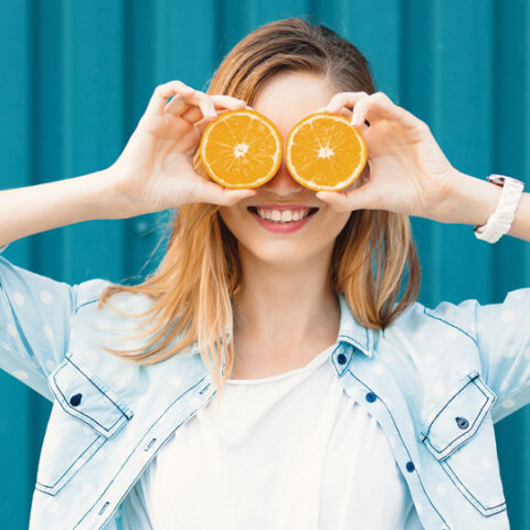 Κορίτσι που κρατάει ροδέλες πορτοκαλιού μπροστά στα μάτια της
