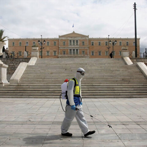 Υπάλληλος του Δήμου Αθηναίων στην πλατεία Συντάγματος με προστατευτική στολή για τον κορωνοϊό