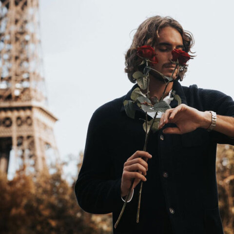 Ο Στέφανος Τσιτσιπάς κοιτά το ρολόι του, κρατώντας ένα κόκκινο τριαντάφυλλο, με φόντο τον Πύργο του Άιφελ στο Παρίσι