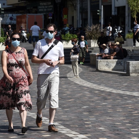 Πολίτες περπατούν στο δρόμο φορώντας μάσκα