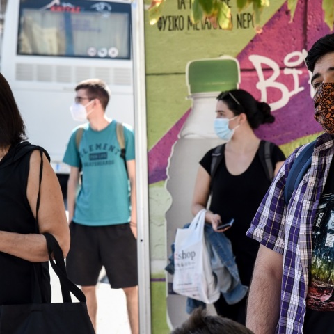Πολίτες που φορούν μάσκες στη στάση του λεωφορείου