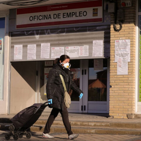 Κορωνοϊός στην Ισπανία: Γυναίκα με προστατευτική μάσκα περνά μπροστά από γραφείο ευρέσεως εργασίας στη Μαδρίτη