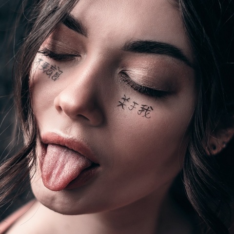 Πορτραίτο μελαχρινής κοπέλας με κλειστά μάτια και τη γλώσσα έξω