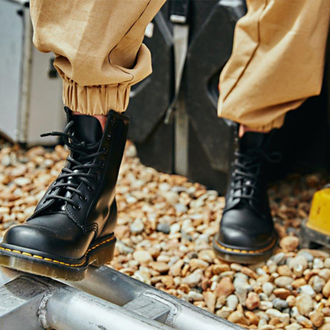 Φωτογραφία εστιασμένη σε πόδια που φορούν μαύρα μποτάκια