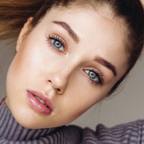 Γυναικείο πρόσωπο με μπλε μάτια και καστανά μαλλιά πιασμένα αλογοουρά