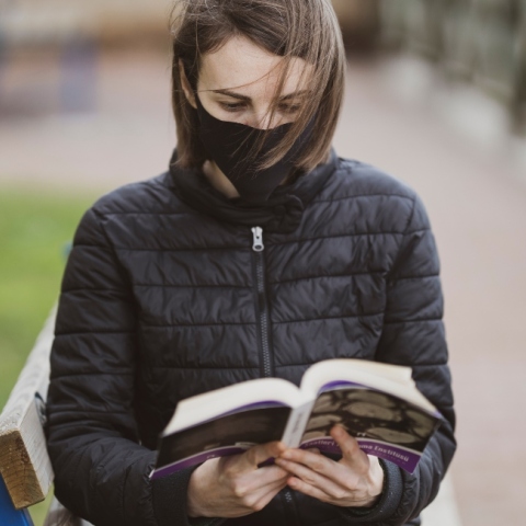 Γυναίκα διαβάζει βιβλίο φορώντας μάσκα