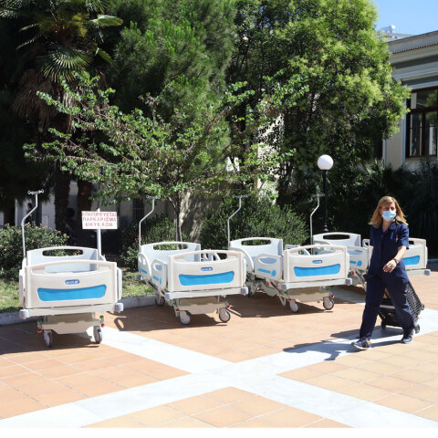 Φορεία στον προαύλιο χώρο νοσοκομείου και γυναικα με ιατρική στολή και μάσκα