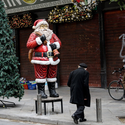 Πολίτες περνούν μπροστά από Άγιο Βασίλη έξω από κλειστά εμπορικά καταστήματα στο κέντρο της Αθήνας εν μέσω lockdown για τον κορωνοϊό