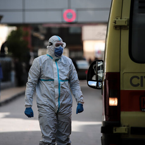 Τραυματιοφορέας με προστατευτική στολή για τον κορωνοϊό δίπλα σε ασθενοφόρο του ΕΚΑΒ