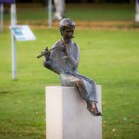 Μπρούτζινο άγαλμα παιδιού που παίζει φλάουτο