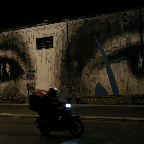 Διανομέας φαγητού περνά με το μηχανάκι μπροστά από τοιχογραφία σε κεντρικό δρόμο της Αθήνας εν μέσω lockdown για τον κορωνοϊό