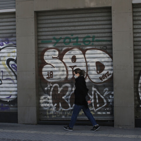 Γυναίκα με μάσκα για τον κορωνοϊό μπροστά από κλειστό κατάστημα στο κέντρο της Αθήνας