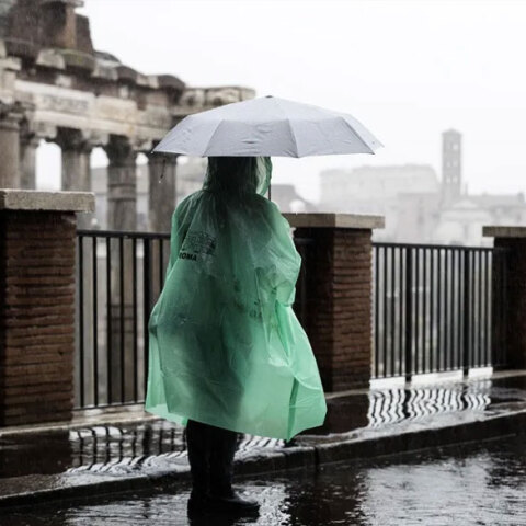Τουρίστρια με ομπρέλα και αδιάβροχο έξω από τη Ρωμαϊκή Αγορά