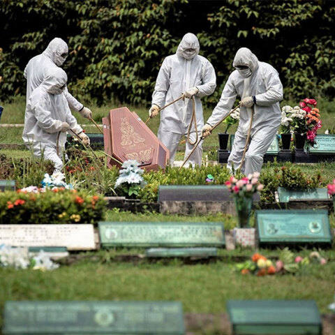 Με προστατευτικές στολές για τον κορωνοϊό, υπάλληλοι γραφείου τελετών στο Σάο Πάολο στη Βραζιλία κατεβάζουν με σχοινιά το φέρετρο νεκρού