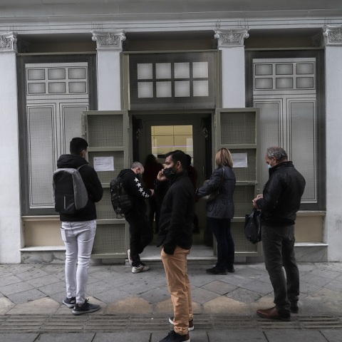 Πολίτες φορώντας μάσκα αναμένουν έξω από τράπεζα