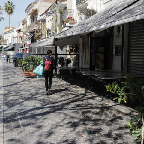 Γυναίκα με τσάντα στην πλάτη περπατά σε πεζόδρομο στο κέντρο της Αθήνας με φόντο τα κλειστά μαγαζιά εν μέσω lockdown