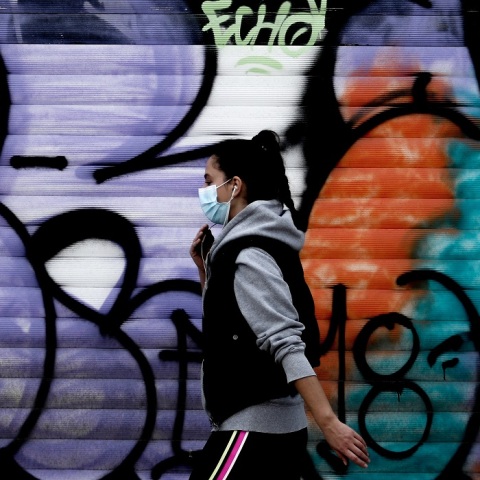 Στιγμιότυπο από το lockdown - Κοπέλα περπατά φορώντας μάσκα