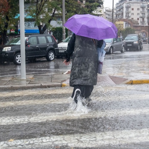 Γυναίκα με ομπρέλα σε πλημμυρισμένο δρόμο 
