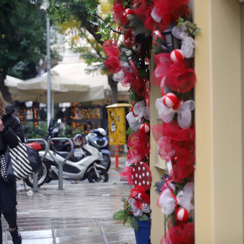 Γυναίκα μιλά στο κινητό έξω από κατάστημα με χριστουγεννιάτικα στη Θεσσαλονίκη