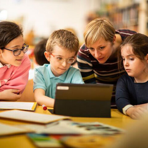 Ομάδα παιδιών και δασκάλων μπροστά σε υπολογιστή