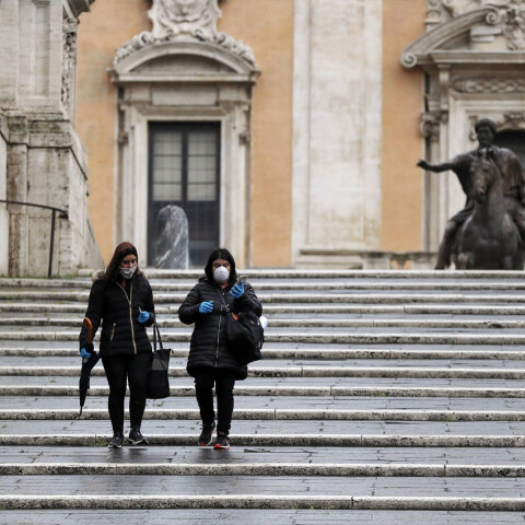 Γυναίκες με προστατευτική μάσκα για τον κορωνοϊό κατεβαίνουν τις σκάλες στο Καπιτώλιο με φόντο το άγαλμα του Μάρκου Αυρηλίου