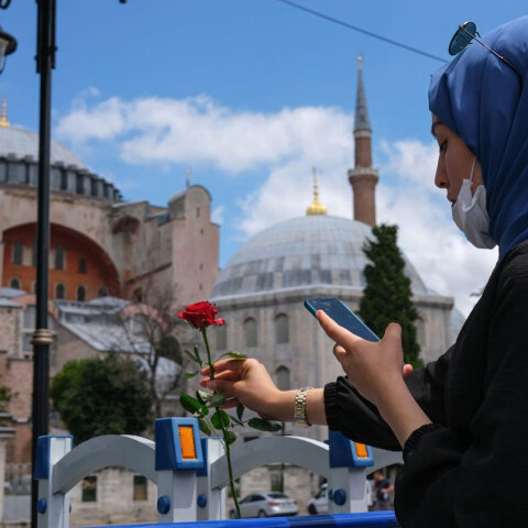 Γυναίκα με μαντήλα και μάσκα για τον κορωνοϊό αφήνει ένα κόκκινο τριαντάφυλλο μπροστά στην Αγία Σοφία στην Κωνσταντινούπολη