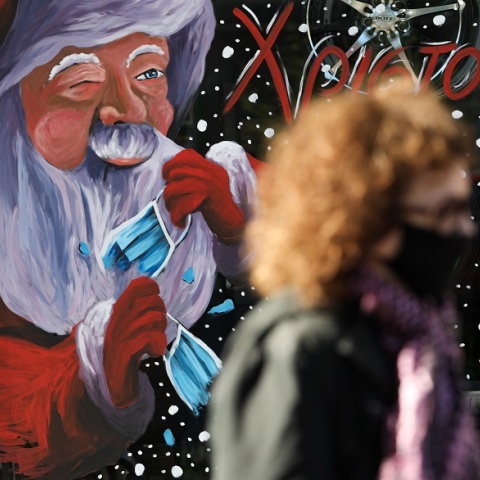 Γυναίκα με μάσκα μπροστά από χριστουγεννιάτικη βιτρίνα