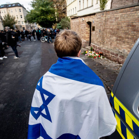 Νεαρός με τη σημαία του Ισραήλ στην πλάτη μπροστά από την εβραϊκή συναγωγή στη γερμανική πόλη Χάλλε