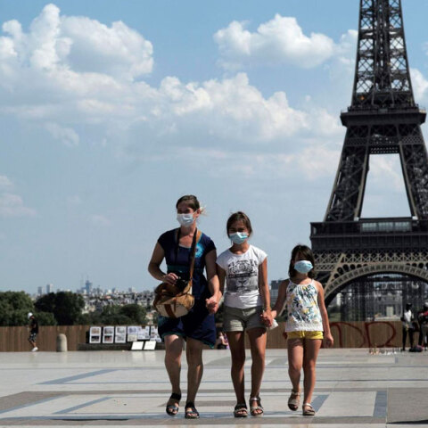 Γαλλία: Τουρίστες με μάσκες για τον κορωνοϊό με φόντο τον Πύργο του Άιφελ στο Παρίσι