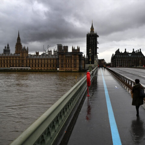 Γυναίκα με μάσκα για τον κορωνοϊό διασχίζει τη γέφυρα Westminster στο Λονδίνο εν μέσω lockdown για τον κορωνοϊό
