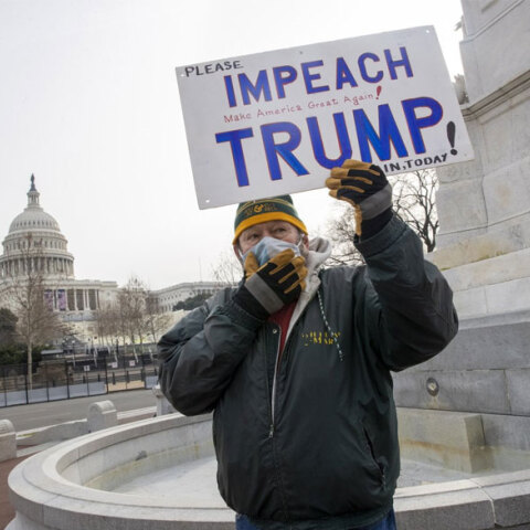 Άνδρας με μάσκα για τον κορωνοϊό ζητά την παραπομπή Τραμπ με φόντο το Καπιτώλιο