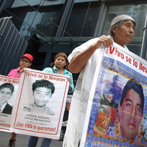 Γονείς κρατούν πανό με τις φωτογραφίες των παιδιών τους που εξαφανίστηκαν 