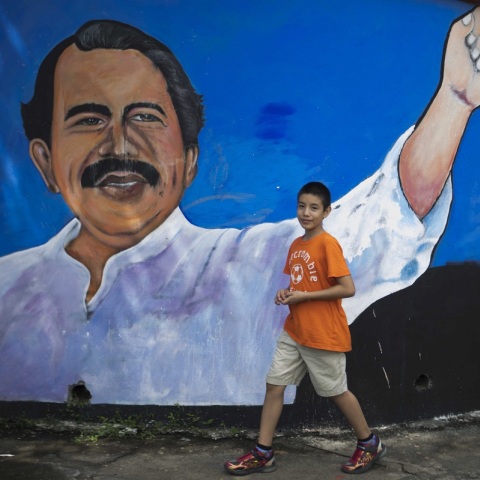 Παιδί κοιτάζει την κάμερα φωτογράφου με φόντο ένα γκράφιτι που απεικονίζει τον Ντανιέλ Ορτέγκα στη Νικαράγουα