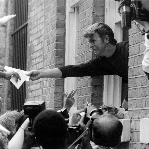 Ο Ντέιβιντ Μπόουι απλώνει το χέρι του από το παράθυρο του σπιτιού του σε θαυμαστές