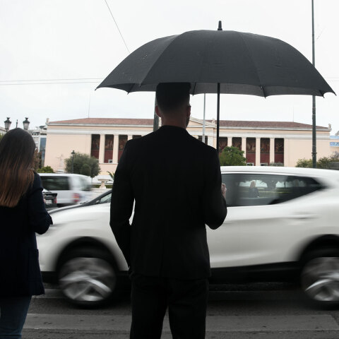 Lockdown στην Αττική: Νεαρός με ομπρέλα στη βροχερή Αθήνα