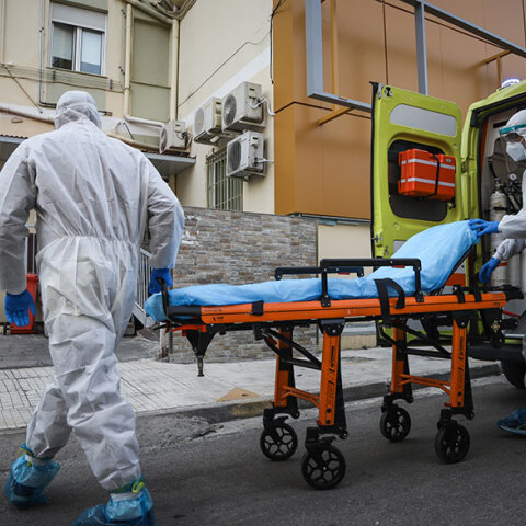 Υγειονομικοί του ΕΚΑΒ με προστατευτικές στολές ετοιμάζονται να μεταφέρουν σε φορείο νέο ασθενή με κορωνοϊό
