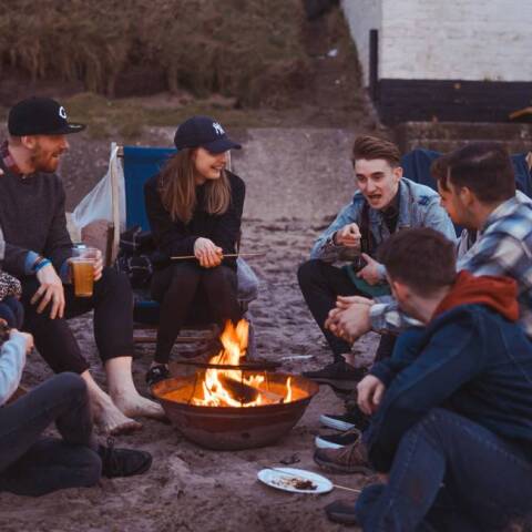 Φίλοι μαζεμένοι γύρω από τη φωτιά στην παραλία