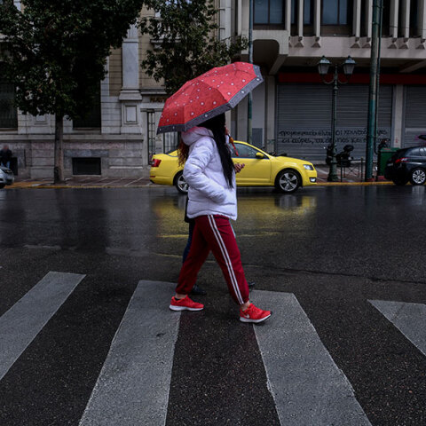 Αττική - Lockdown: Κοπέλα με ομπρέλα διασχίζει διάβαση πεζών στην Αθήνα