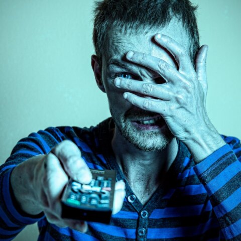 Άνδρας που κρύβει το πρόσωπό του και κρατά τηλεκοντρόλ