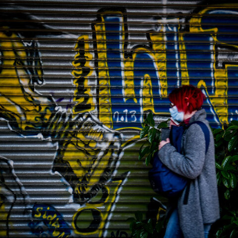 Αττική - Κορωνοϊός: Γυναίκα με μάσκα περνά μπροστά από γκράφιτι στο κέντρο της Αθήνας