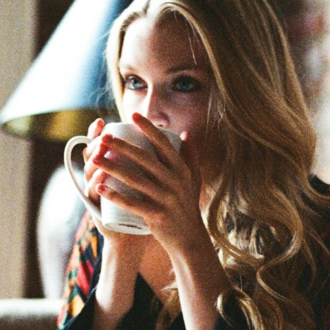 Γυναίκα με φλοράλ φόρεμα πίνει καφέ και διαβάζει βιβλίο