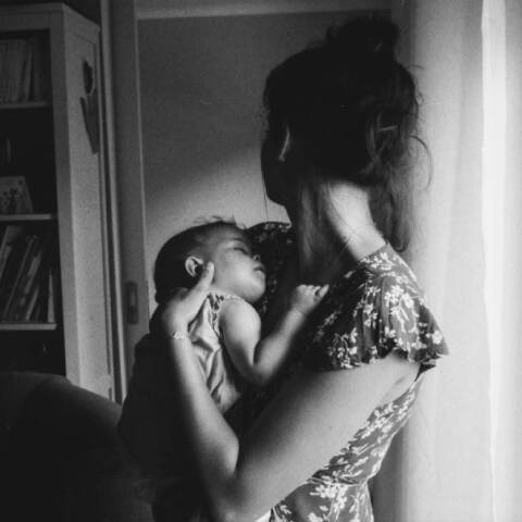 Ασπρόμαυρη φωτογραφία με μια μαμά που κρατάει στην αγκαλιά της ένα μωρό