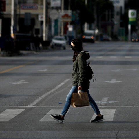 Κορωνοϊός - Ελλάδα: Γυναίκα με μάσκα διασχίζει διάβαση πεζών στην Αθήνα