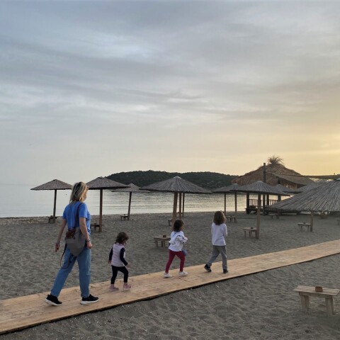 Γυναίκα περπατά σε παραλία με τρία παιδιά