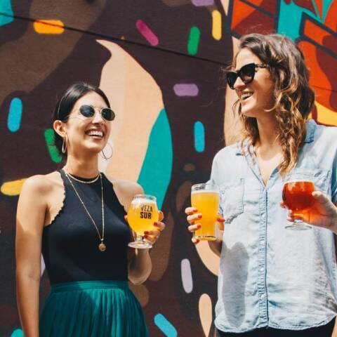 Τέσσερις φίλες που πίνουν ποτό, συζητάνε και γελάνε